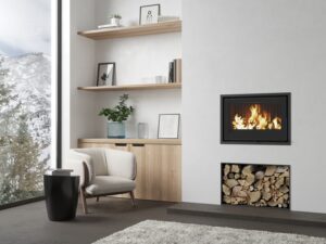Insert à bois Dovre Vista 701i encastré dans un mur blanc au-dessus d’un bûcher