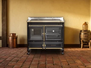 Cuisinière à bois Archambaud Légende 100 noire et laiton dans une cuisine de ferme normande, sol en briques de terre cuite