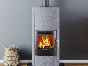 Poêle à bois ollaire Lorflam Solstrål 2 aux formes arrondies, allumé dans un salon