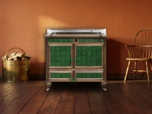 Cuisinière à bois Archambaud Origine 100 en faïence verte et bronze dans une cuisine d’auberge de campagne, mur ocre rouge et parquet ancien