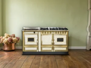Cuisinière mixte Archambaud Origine 160 en faïence crème et laiton dans une cuisine de maison du Val de Loire, parquet de chêne et horloge comtoise