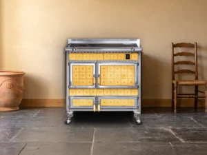 Cuisinière à bois Archambaud Origine 90 en faïence jaune ocre et chrome dans une cuisine de ferme du Périgord, sol en dalles de pierre