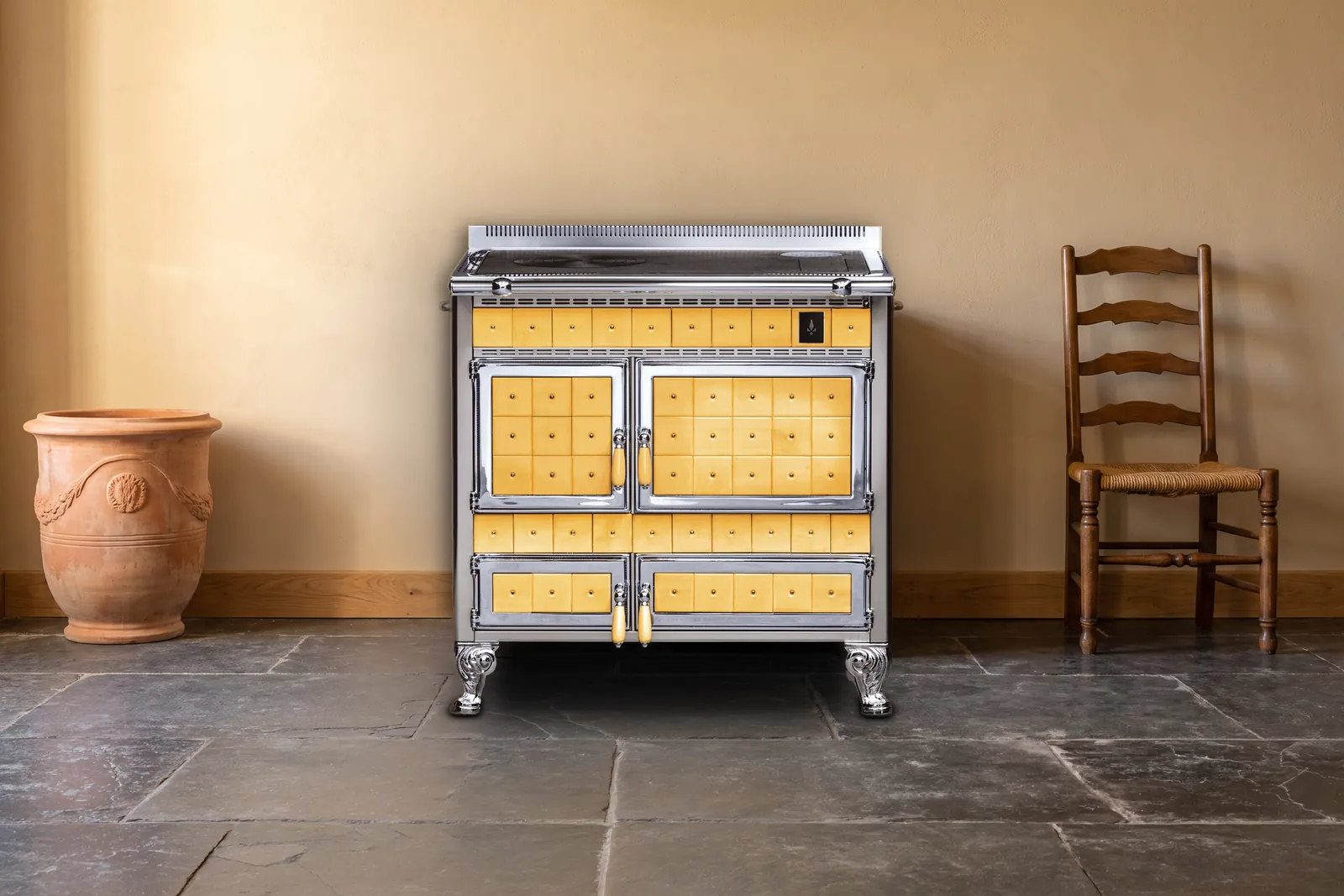 Cuisinière à bois Archambaud Origine 90 en faïence jaune ocre et chrome dans une cuisine de ferme du Périgord, sol en dalles de pierre