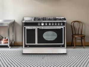 Cuisinière mixte Archambaud Prestige 120 noire et inox dans une cuisine de bistrot parisien, sol en mosaïque noire et blanche