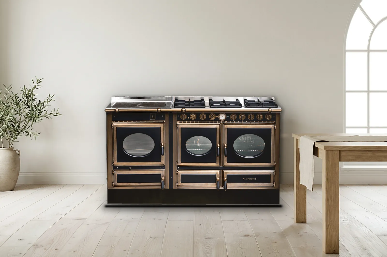 Cuisinière mixte Archambaud Prestige 160 noire et bronze dans une cuisine scandinave, sol clair et table en chêne
