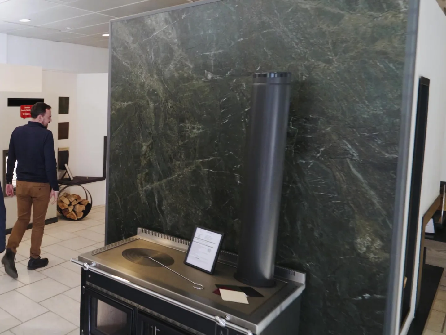 Cuisinière à bois exposée devant un panneau en marbre vert au showroom de Vitré