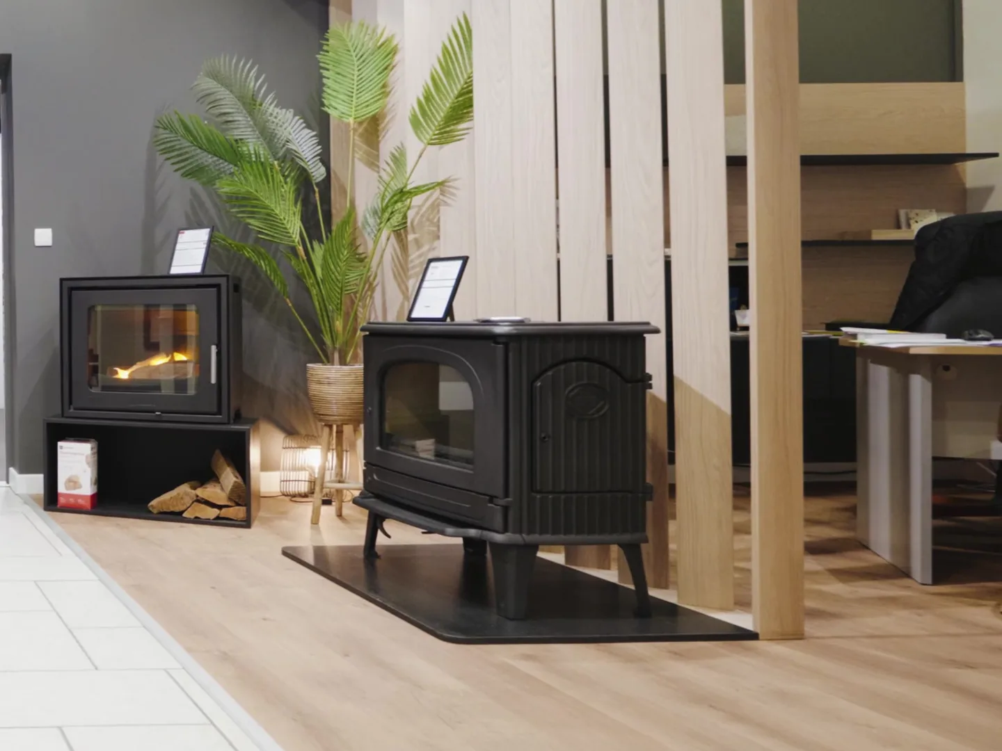 Poêle à bois en fonte noire sur son socle, showroom Cheminées Jouvin