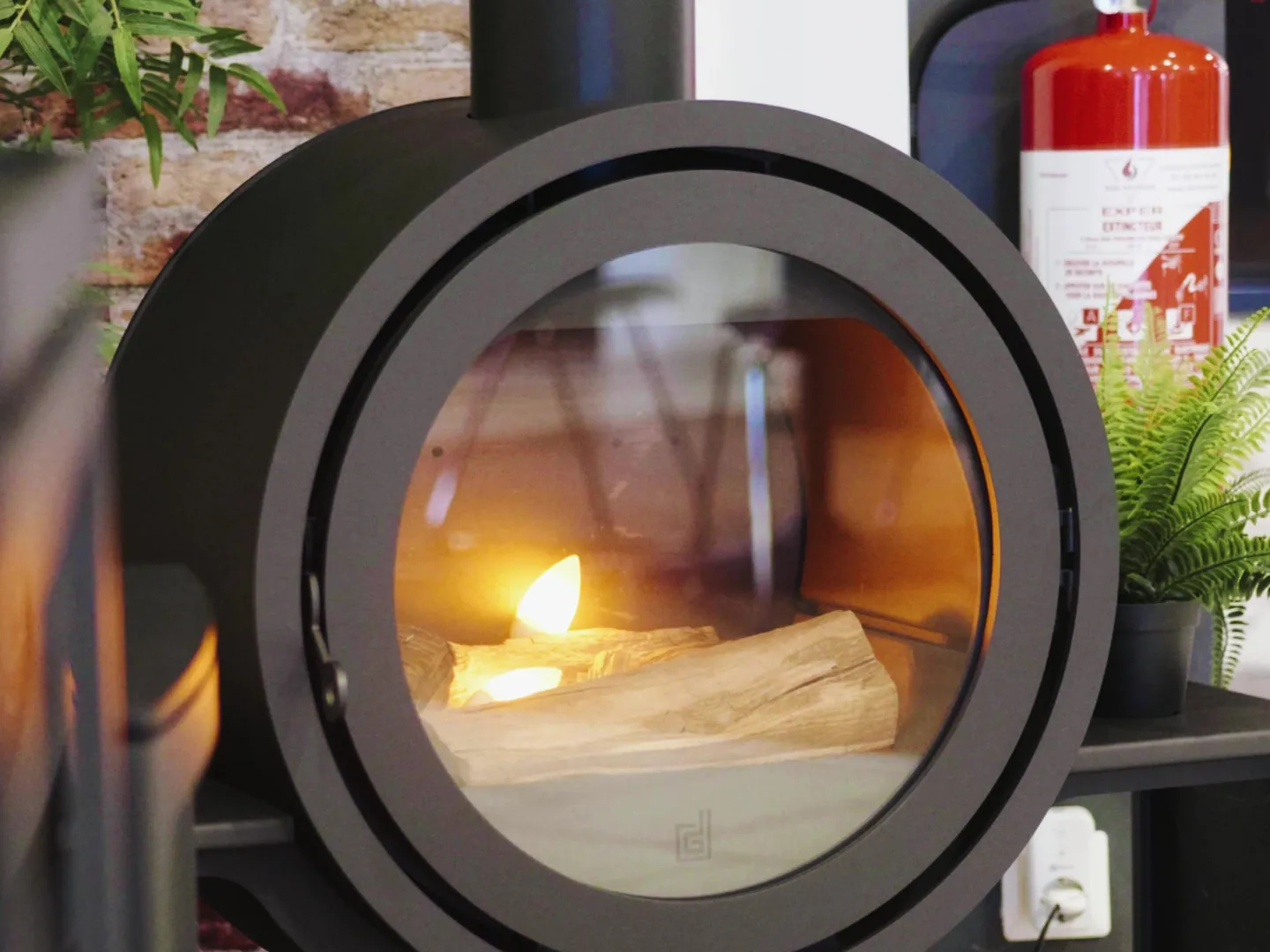 Poêle à bois rond, feu allumé, exposé au showroom Cheminées Jouvin de Vitré
